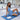 Woman in blue athletic wear sitting on a blue yoga mat with a book.